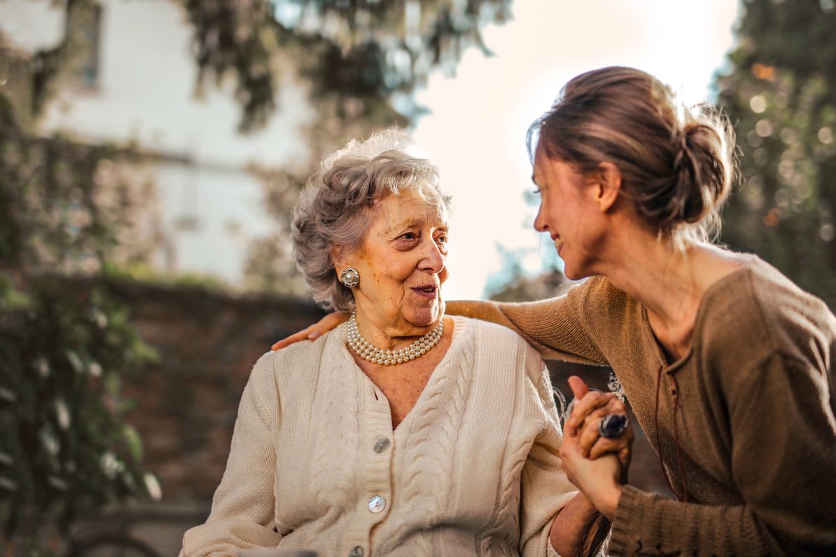 A caregiver and an older woman laughing warmly together